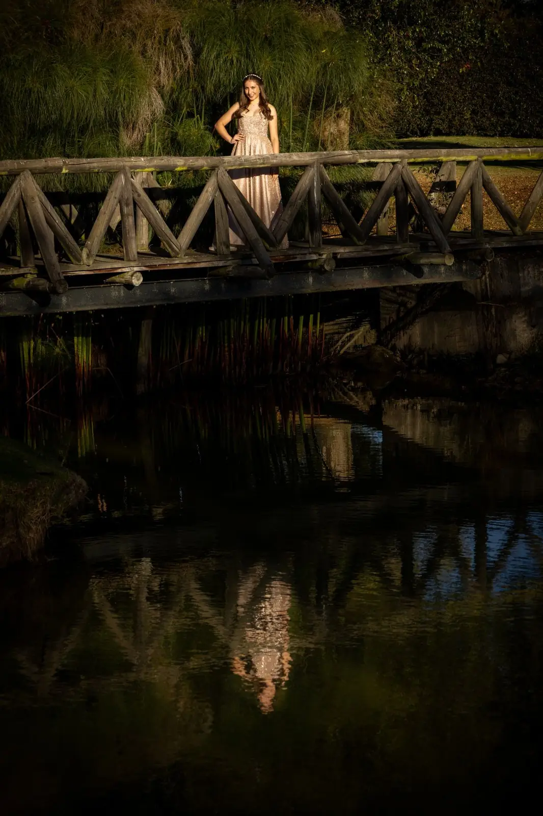 Quinceañera en un puente de madera con reflejo en el agua