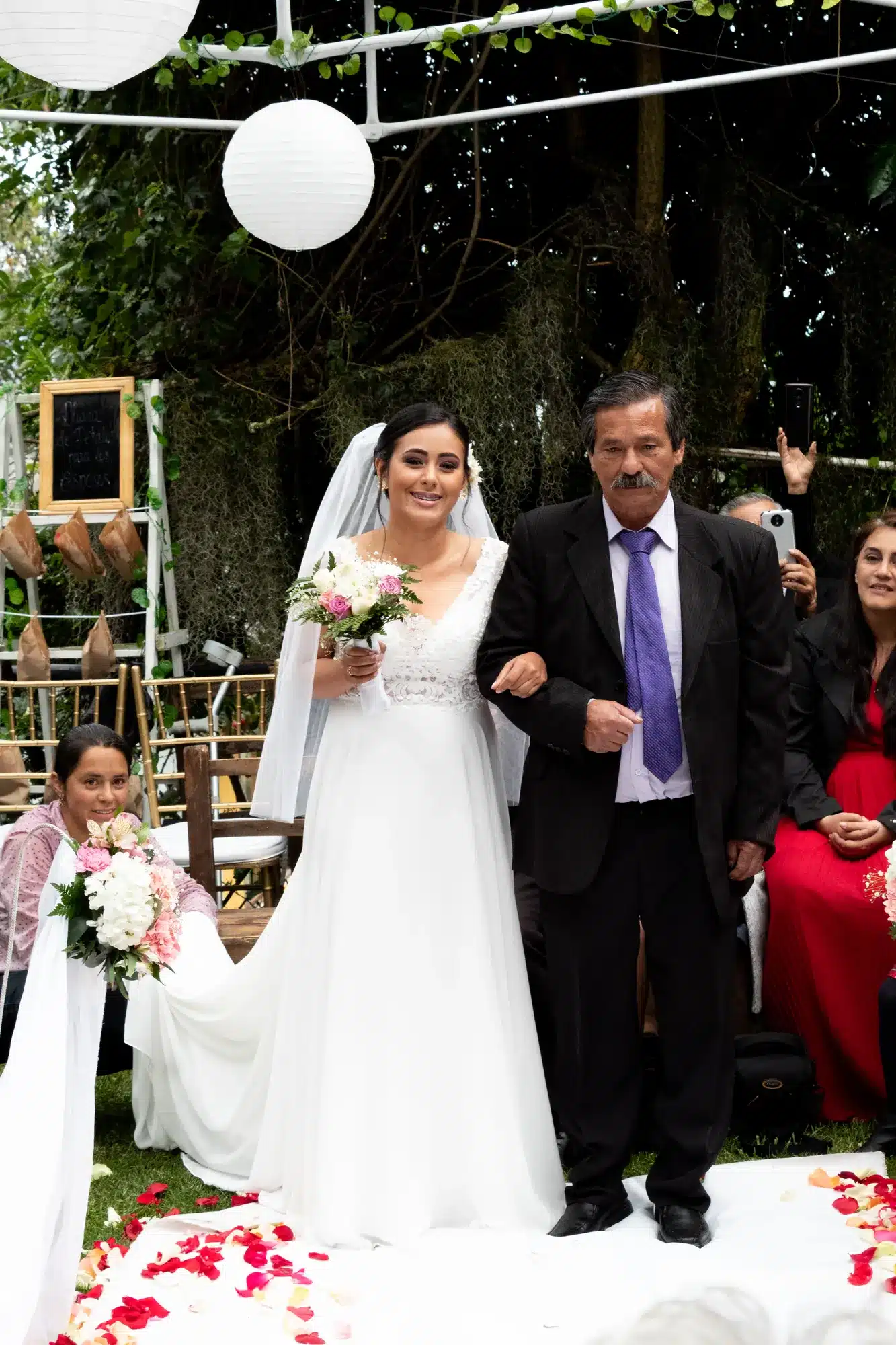 Novia entrando del brazo de su padre sobre pétalos