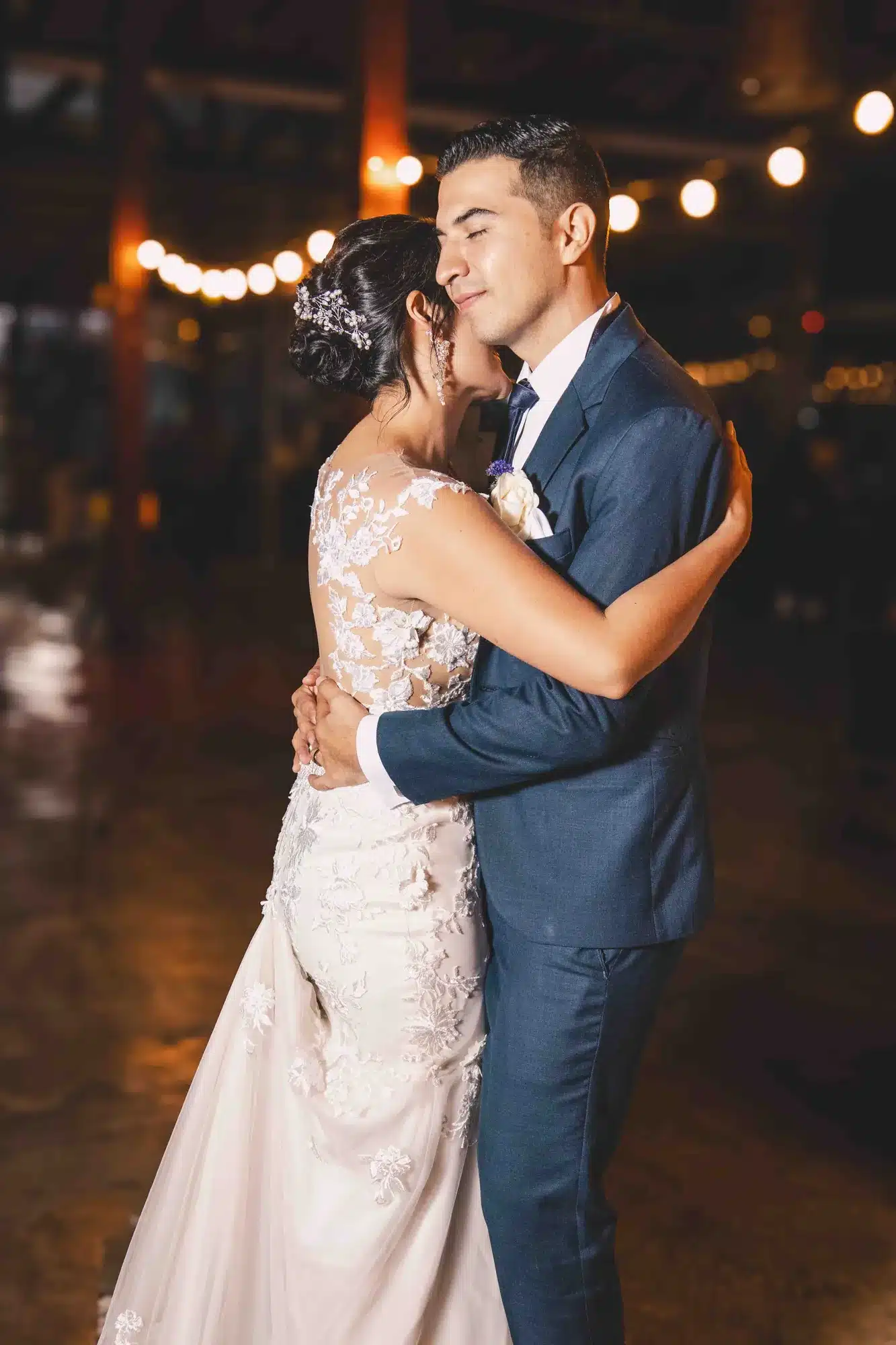 Novios abrazados bajo luces de fiesta