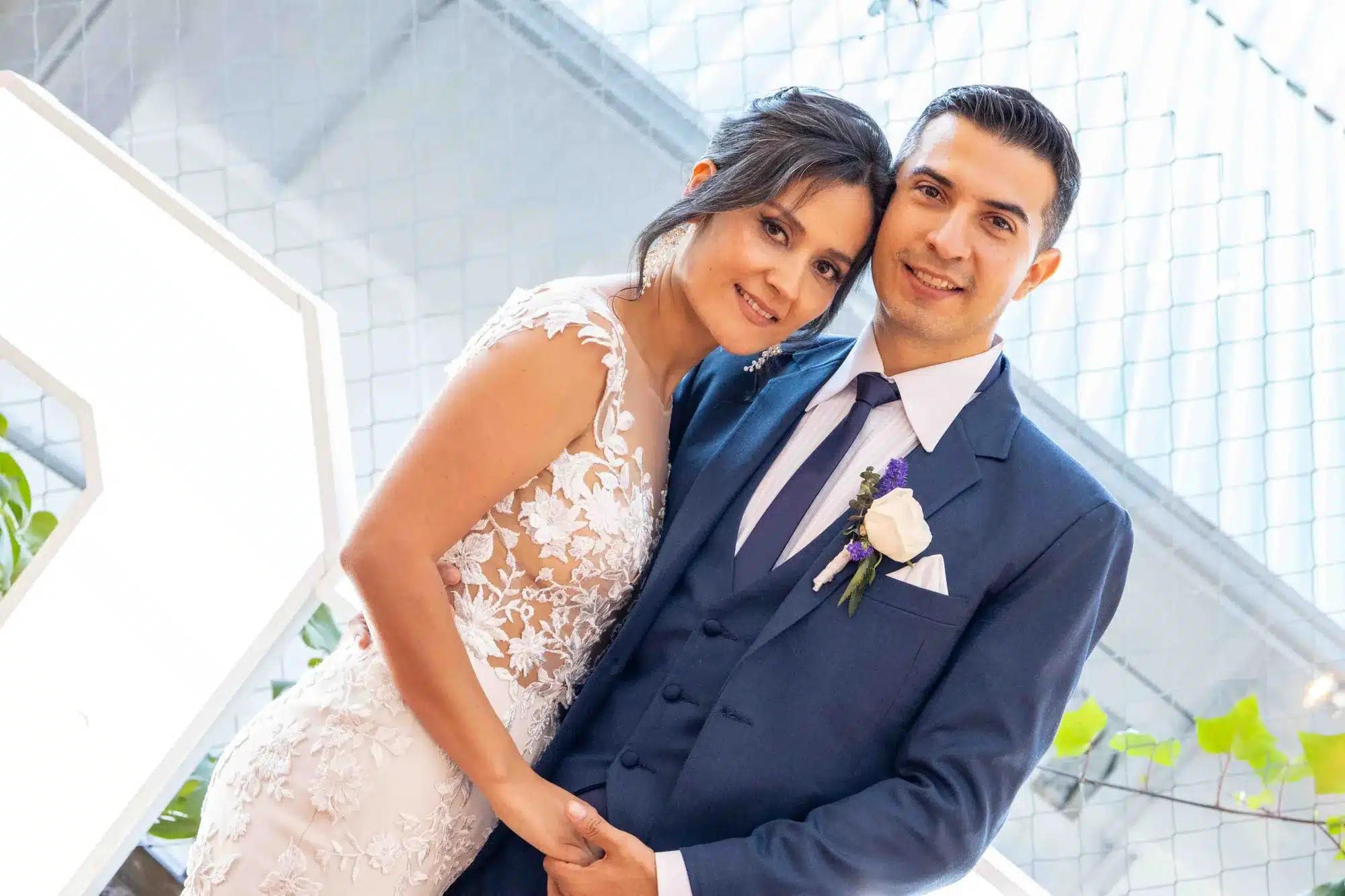 Novios abrazados bajo una estructura de cristal