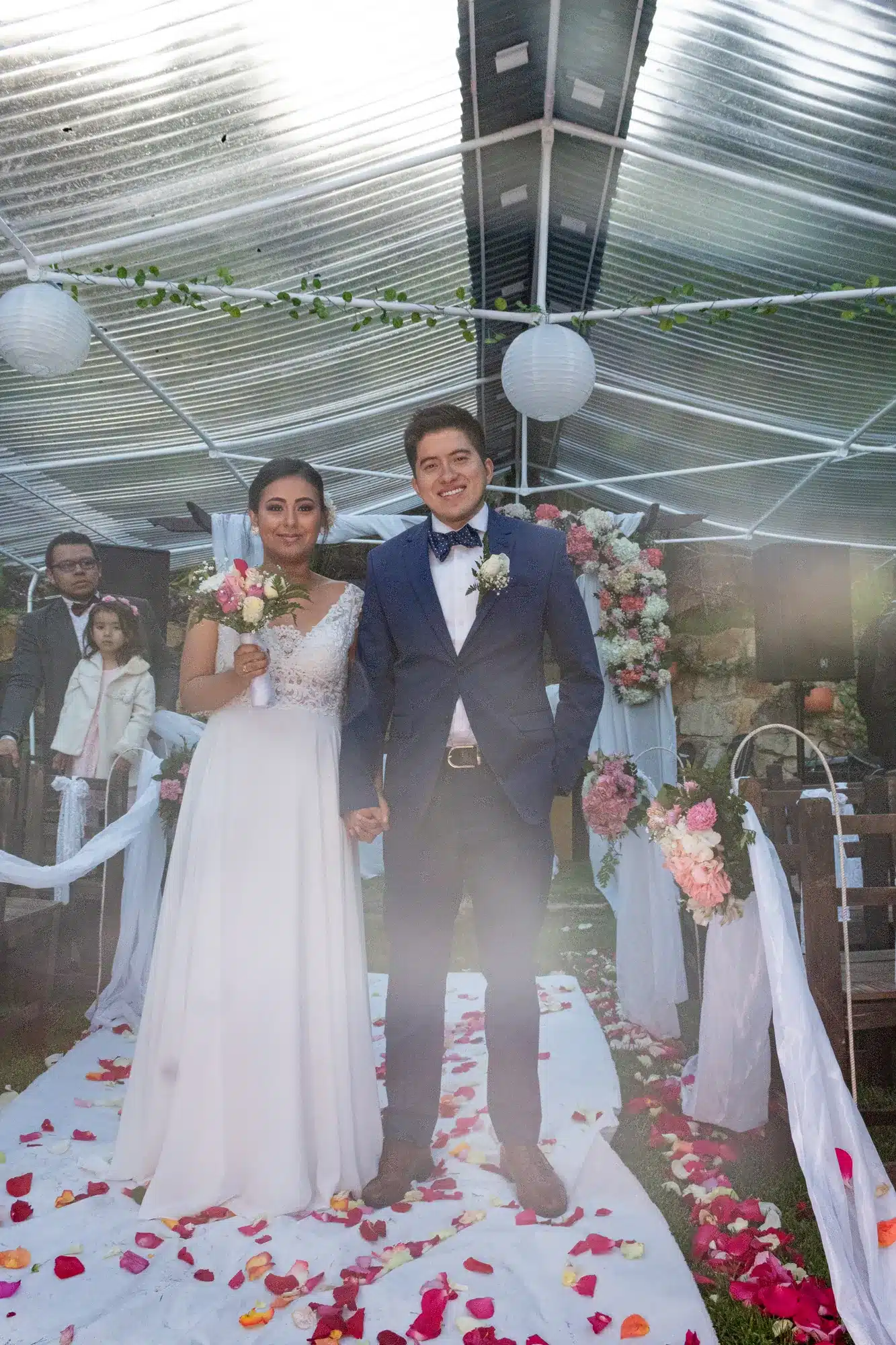 Novios en el pasillo de una ceremonia con pétalos