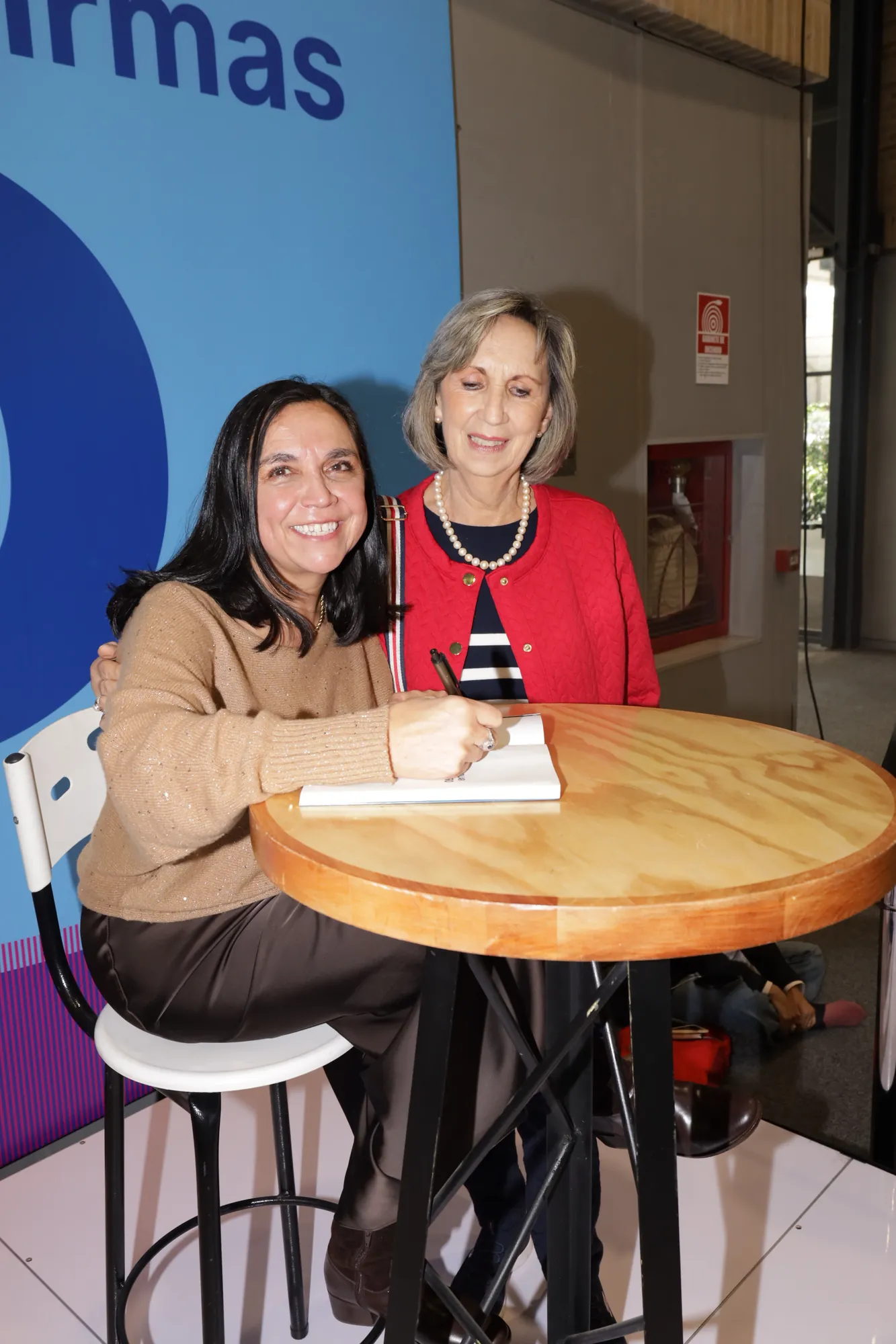 Autora firmando libros en una feria editorial