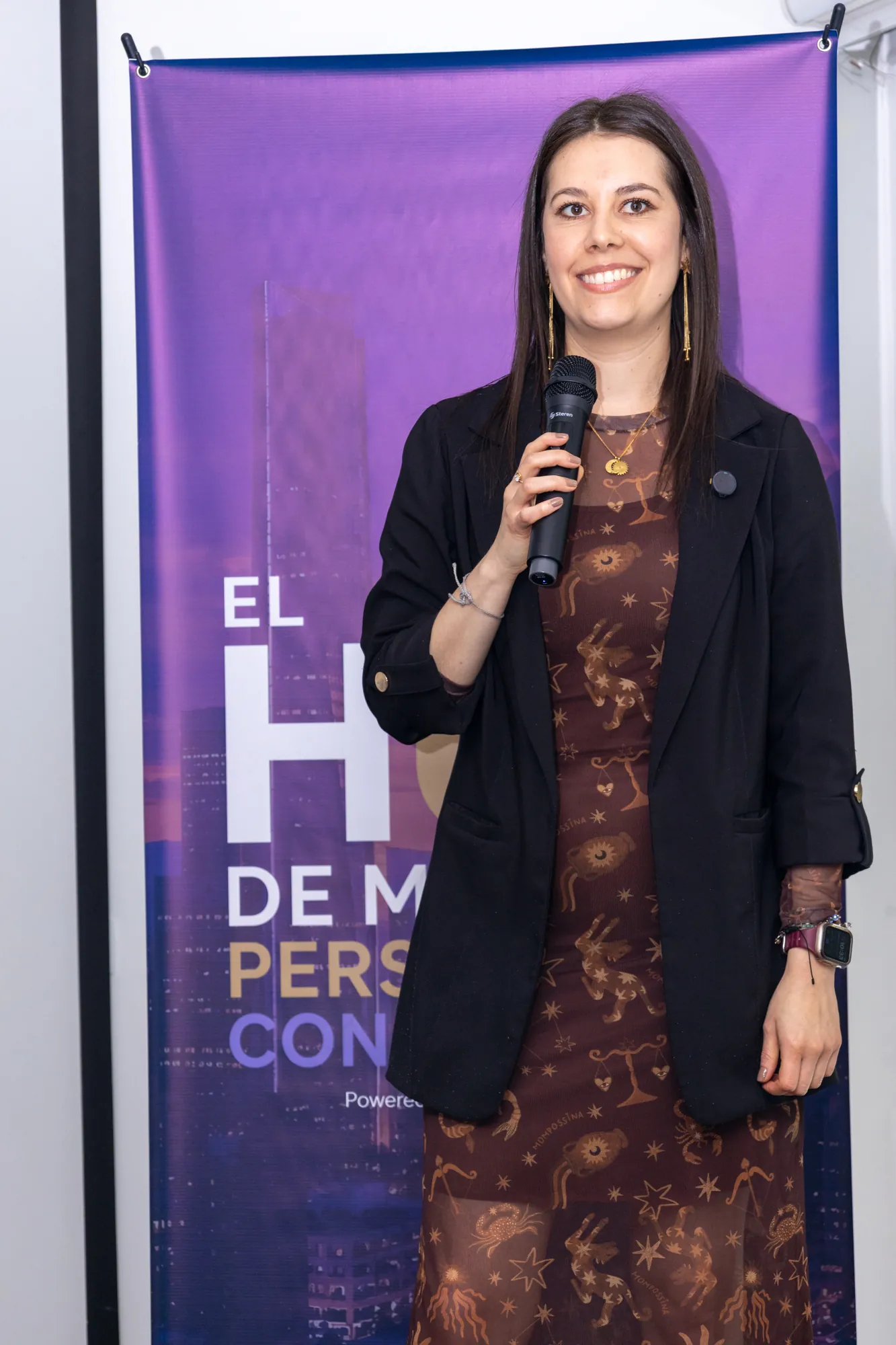 Conferencista con micrófono ante un banner de marca