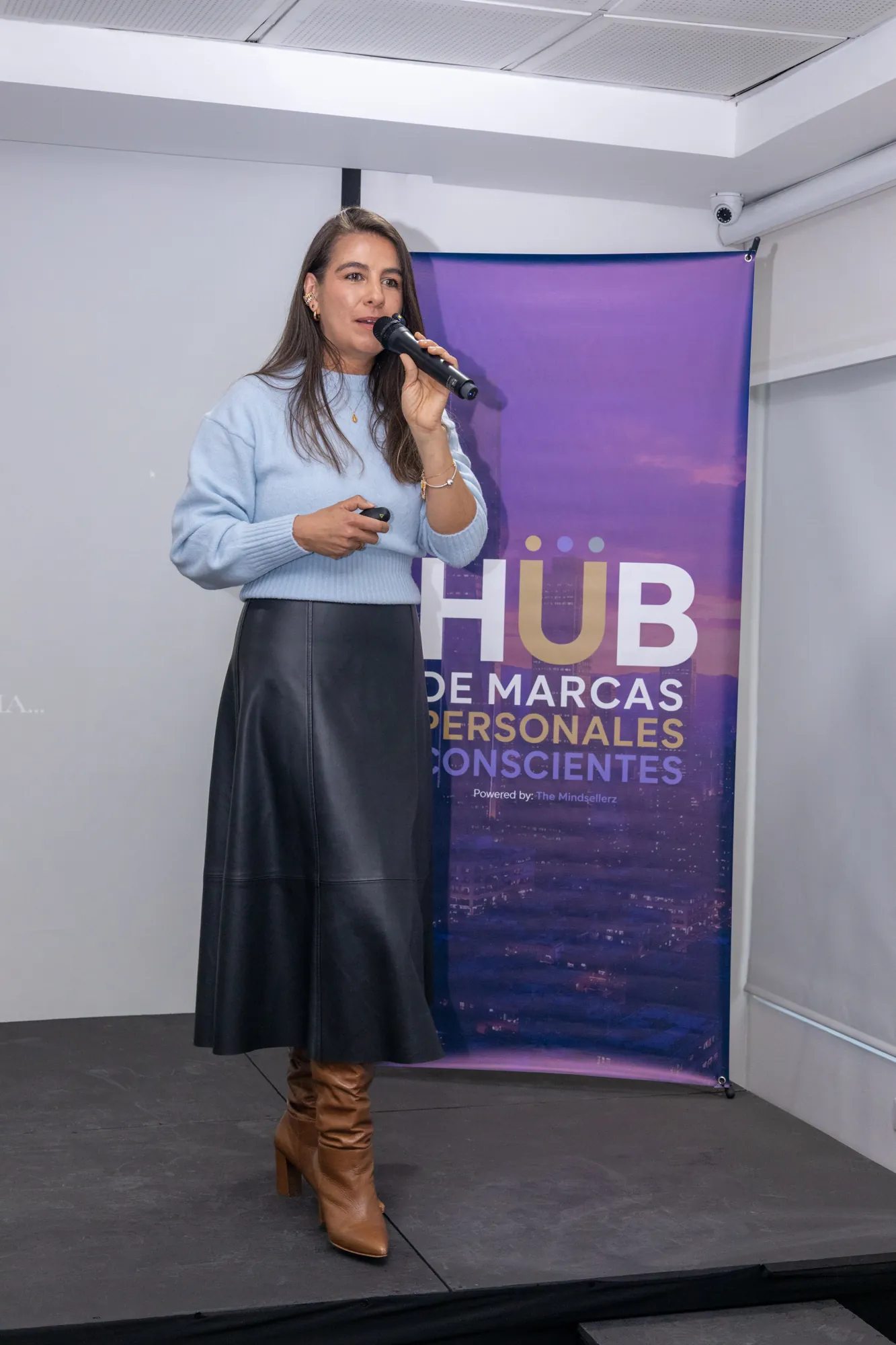 Conferencista con vestido azul frente al panel del evento