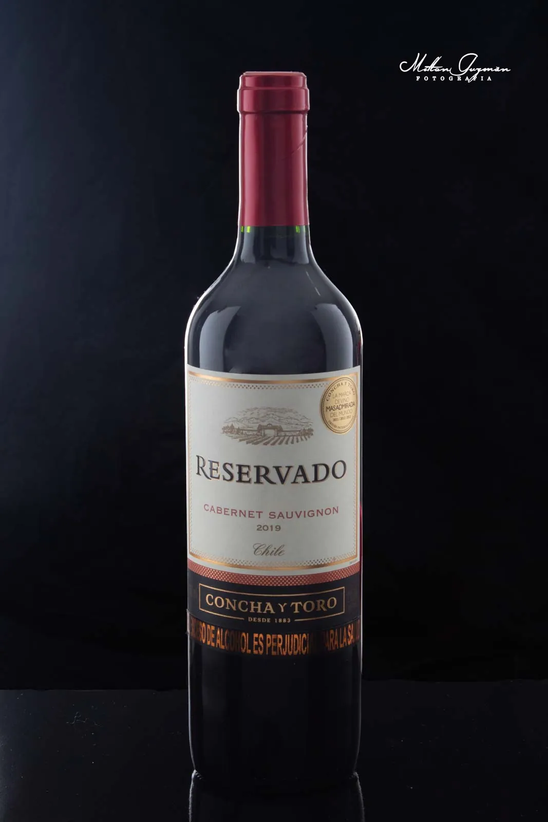 Botella de vino tinto sobre fondo negro reflectante