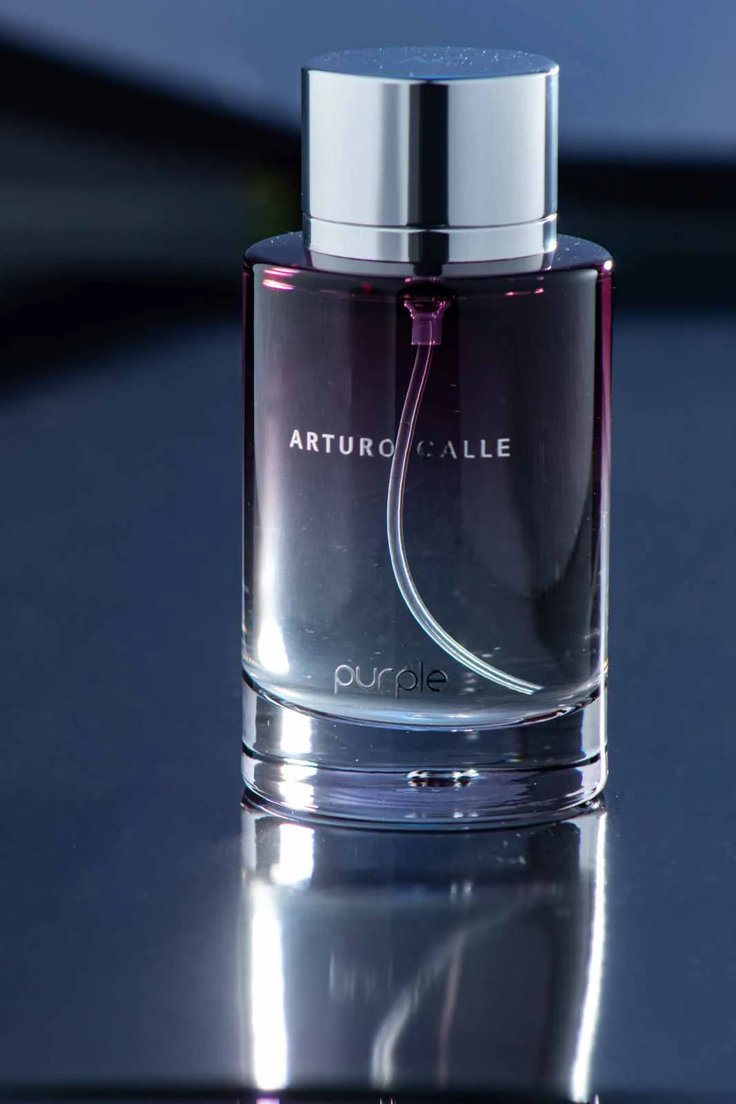 Frasco de perfume sobre superficie azul, fotografía de producto