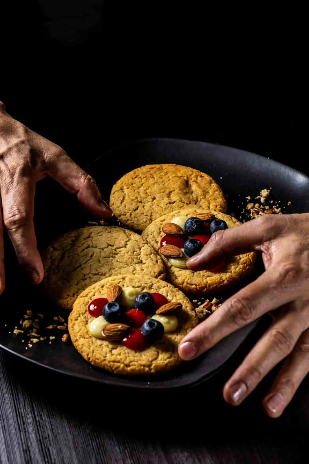 Manos tomando una galleta con frutos rojos