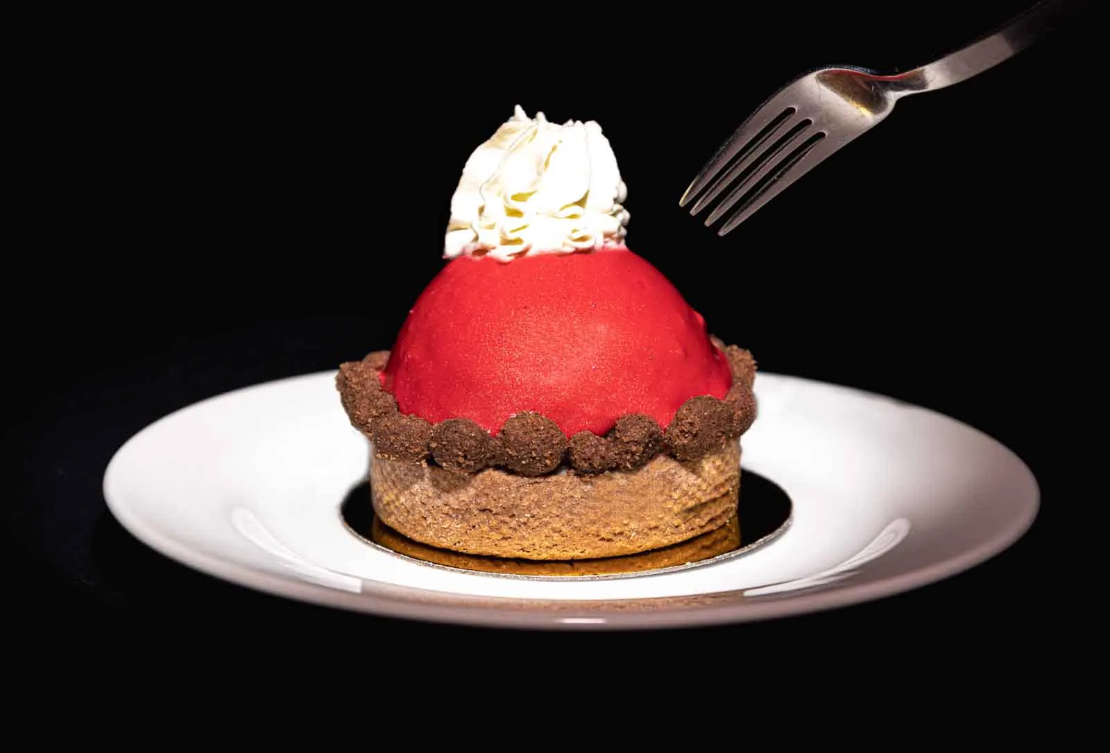 Postre de frutos rojos con crema sobre plato blanco y fondo negro
