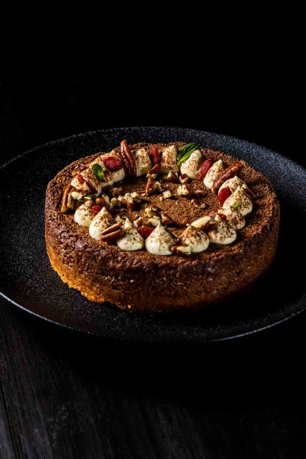 Torta con nueces y crema sobre plato negro