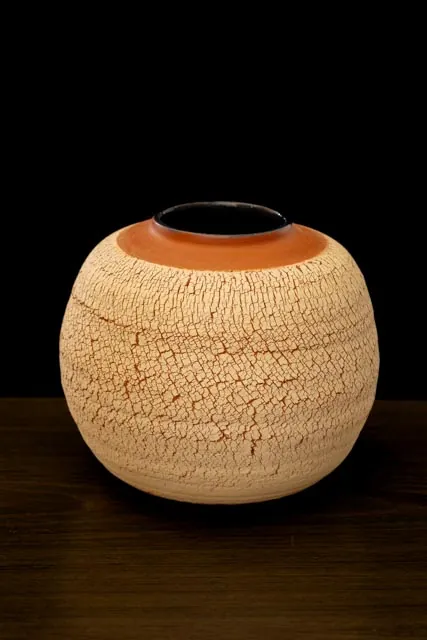 Vasija de cerámica con textura sobre fondo oscuro