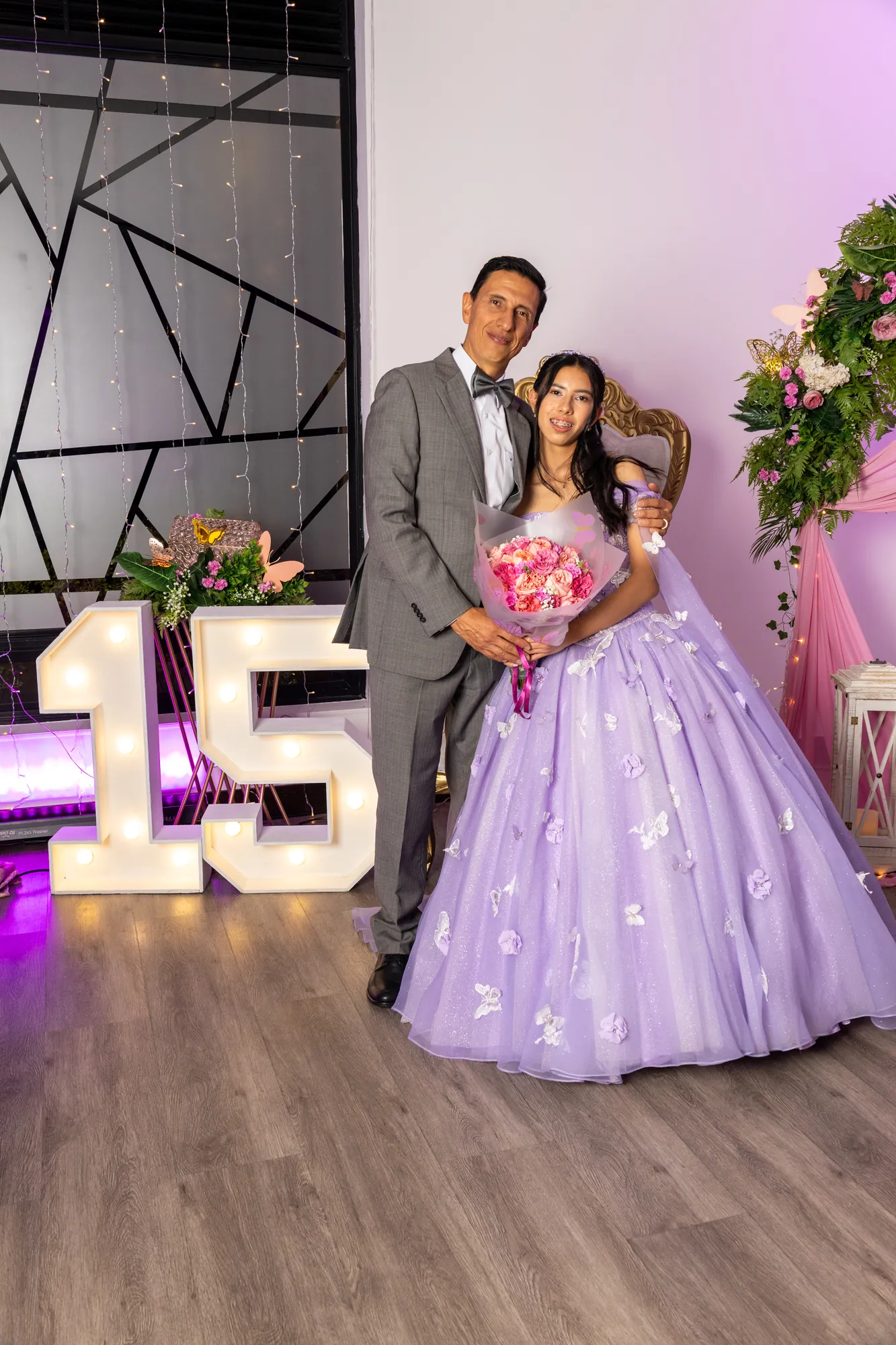 Quinceañera con su padre junto al letrero de 15 años