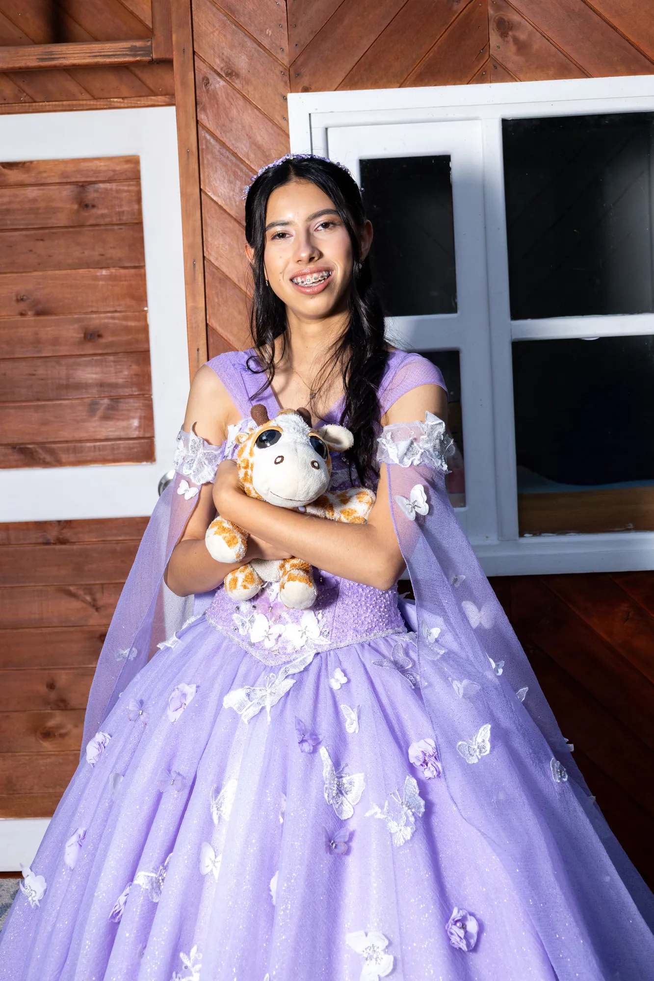 Quinceañera con vestido lila abrazando un peluche