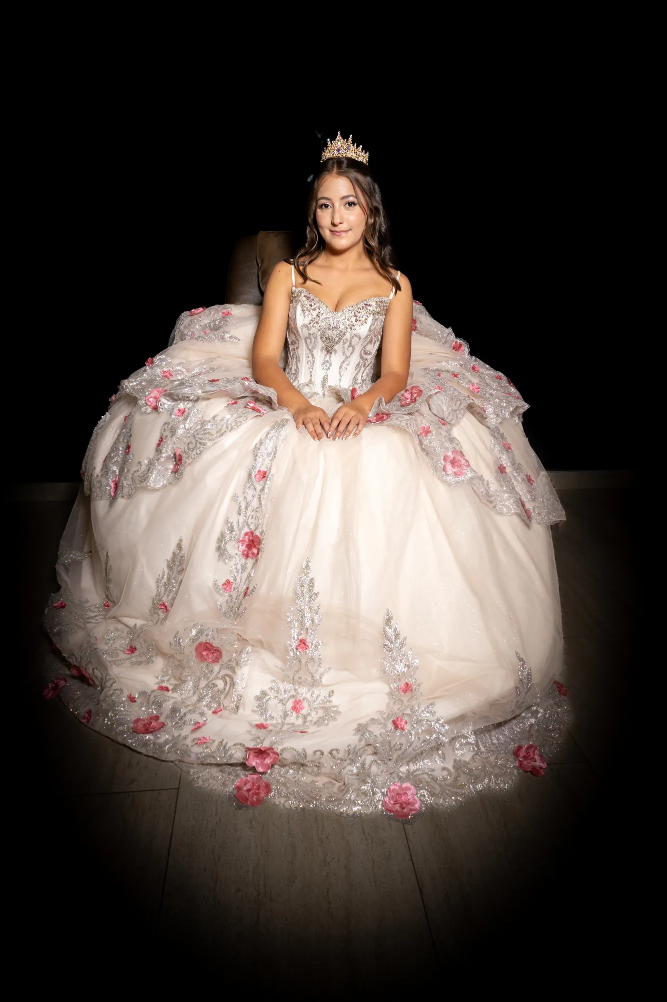 Quinceañera sentada con vestido de vuelo sobre fondo negro